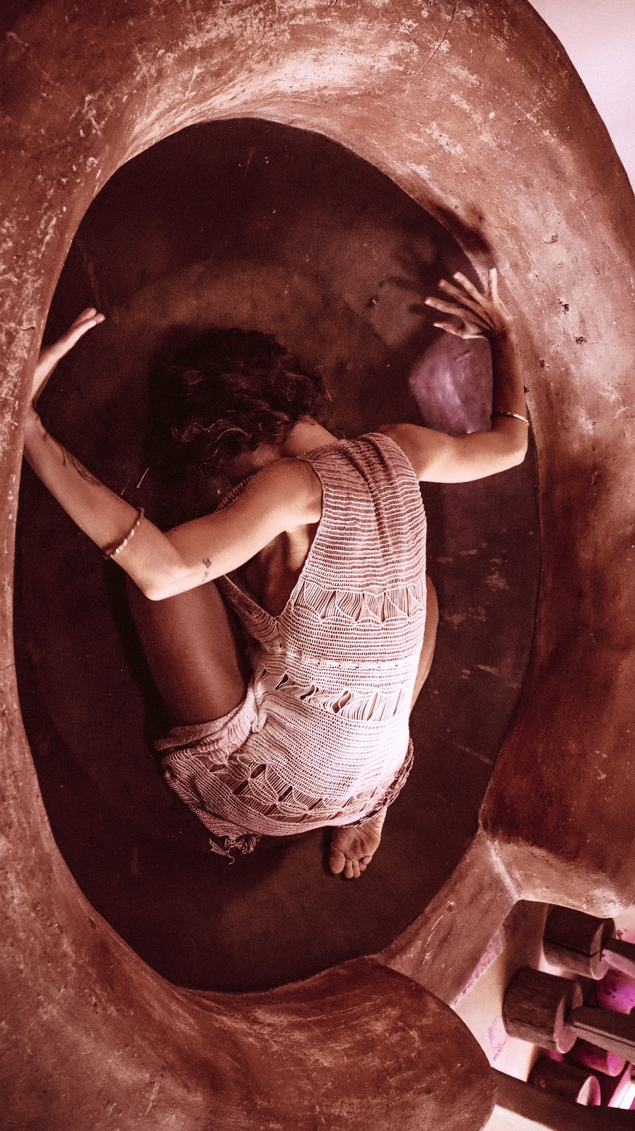 Corpo em movimento entre curvas de uma composição artística terracota