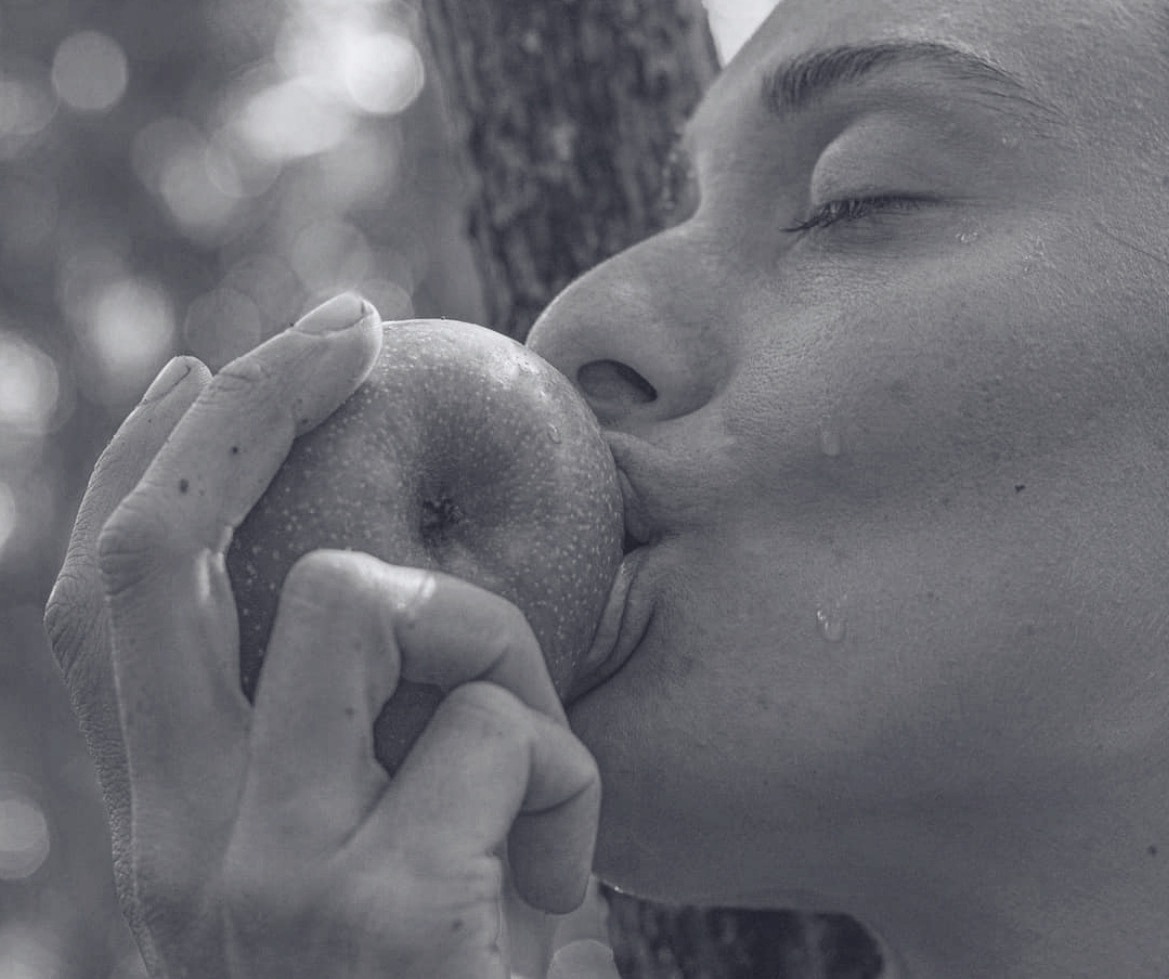Mulher de olhos fechados em contato com um fruto